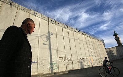 A Palestinian man walks past the Israeli security barrier in the East Jerusalem village of Abu Dis (Kobi Gideon/Flash90)