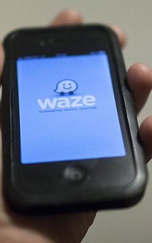 A man holds an iPhone displaying the Waze app (photo credit: Yonatan Sindel/Flash90)