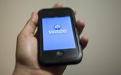 A man holds an iPhone displaying the Waze app (Yonatan Sindel/Flash90)