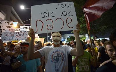 Protesters returned to Tel Aviv on Saturday night. This protester's sign reads 'Bibi, you have burned me too," a reference to budget cuts and Moshe Silman, who self-immolated one year ago. (photo credit: Gili Yaari/ Flash90)