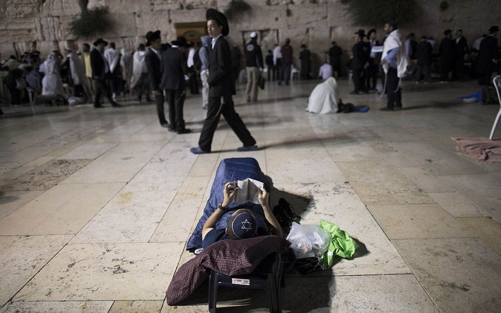 A man laying down as he recites Lamentations on the ninth of Av, at the Western Wall (photo credit: Yonatan Sindel/Flash 90)