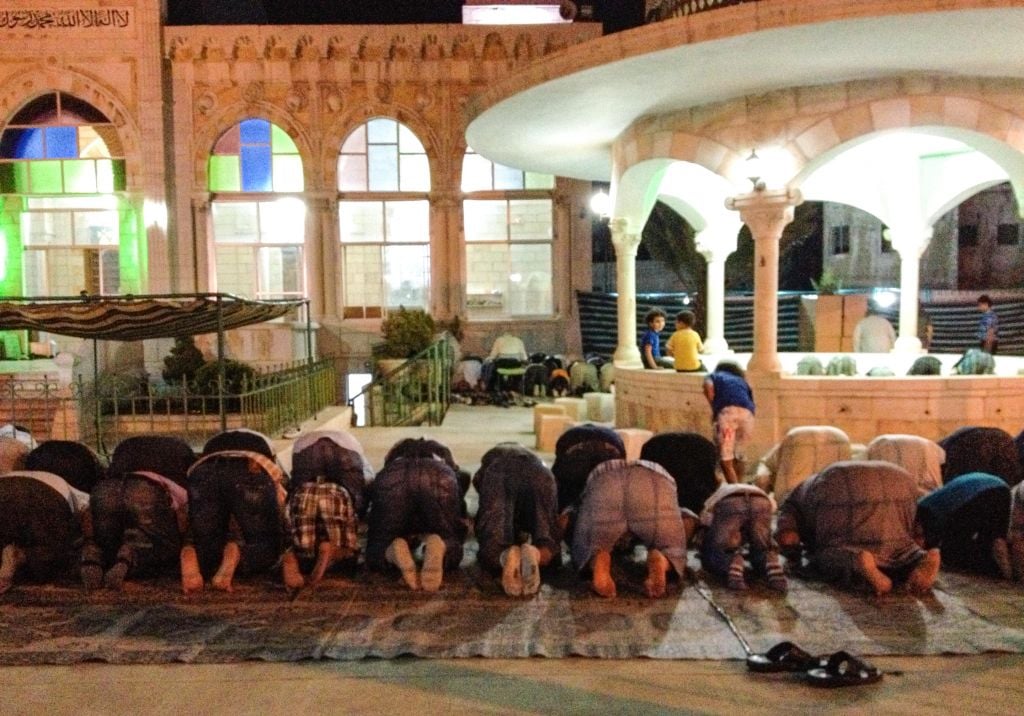 Men engage in communal prayer outside a mosque just before 8 pm, at which time the fast of Ramadan is broken in Amman (photo credit: Michal Shmulovich/Times of Israel)