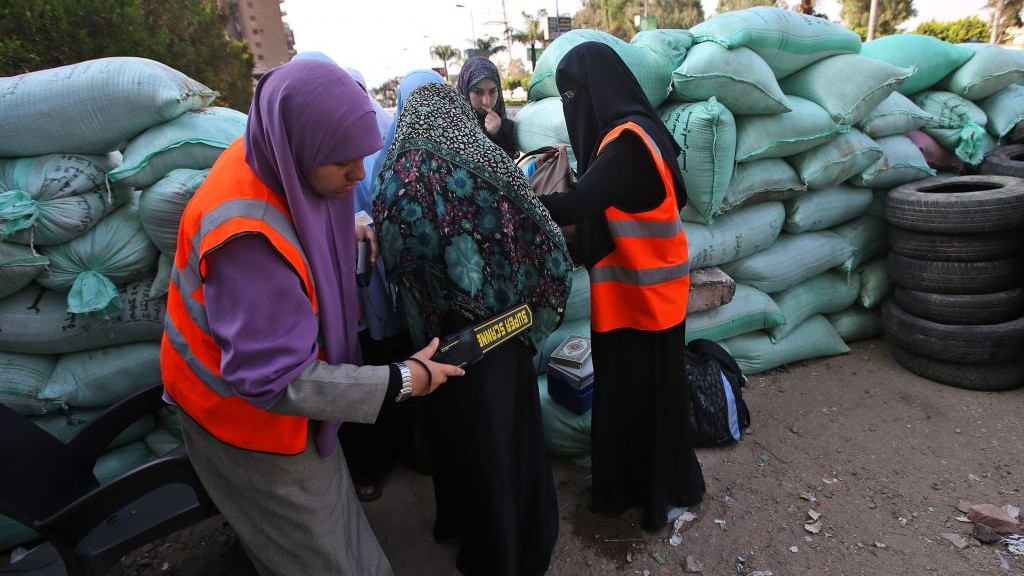 Supporters of Egypt's ousted president Mohammed Morsi check women on Thursday at sand barriers recently set up for women to enter the area where protesters installed their camp at Nasr City in Cairo, Egypt. (photo credit: AP Photo/Hussein Malla) 