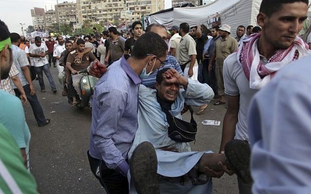Supporters of Egypt's ousted President Mohammed Morsi carry an injured man to a field hospital following clashes with security forces at Nasr City, where pro-Morsi protesters have held a weeks-long sit-in, in Cairo, Egypt on Saturday. (photo credit: AP Photo/Khalil Hamra)