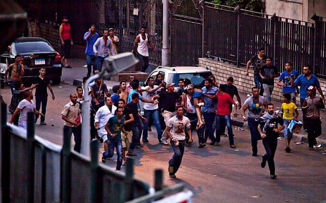 Protesters run with an injured man following clashes in the Kit Kat neighborhood of Giza, Egypt, where Tuesday, July 2 (photo credit: AP/Maya Alleruzzo) Protesters run with an injured man following clashes in the Kit Kat neighborhood of Giza, Egypt, where Tuesday, July 2 (photo credit: AP/Maya Alleruzzo)