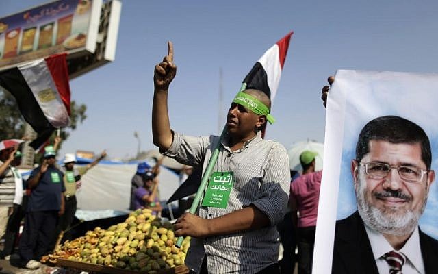 Supporters of Egypt's Islamist president Mohammed Morsi chant slogans during a rally, in Nasser City, Cairo, Egypt, Wednesday, July 3, 2013. The green card with Arabic reads, "stay where you are." (photo credit: AP Photo/Hassan Ammar) Supporters of Egypt's Islamist president Mohammed Morsi chant slogans during a rally, in Nasser City, Cairo, Egypt, Wednesday, July 3, 2013. The green card with Arabic reads, "stay where you are." (photo credit: AP Photo/Hassan Ammar)