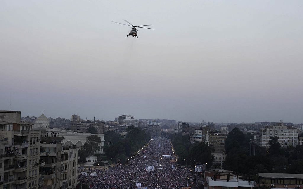 A military helicopter flies over the presidential palace as opponents of Egypt's Islamist President Mohammed Morsi protest in Cairo, Egypt, on Wednesday. (photo credit: AP/Nariman El-Mofty)