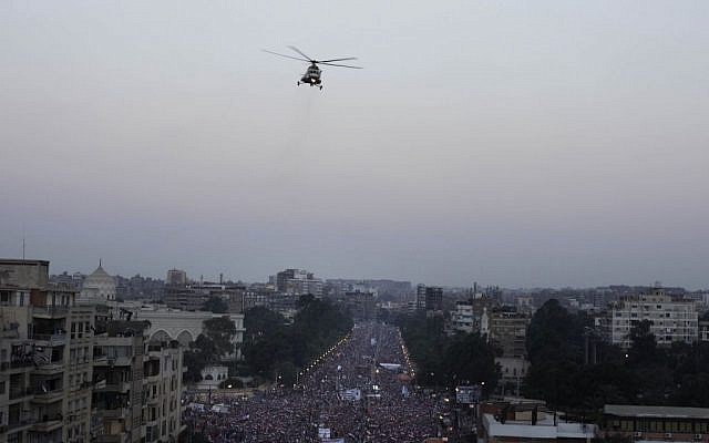A military helicopter flies over the presidential palace as opponents of Egypt's Islamist President Mohammed Morsi protest in Cairo, Egypt, on Wednesday. (photo credit: AP/Nariman El-Mofty)
