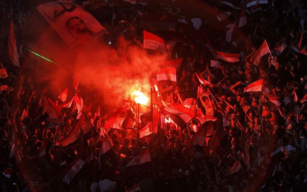 Opponents of Egypt's Islamist President Mohammed Morsi celebrate as they light flares and wave national flags and his picture daubed with the Arabic word for "leave", in Tahrir Square in Cairo, Egypt, Wednesday, July 3, 2013.  (photo credit:AP/Amr Nabil)