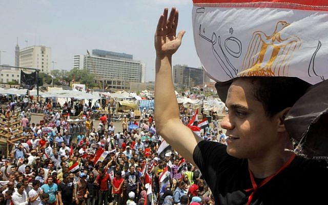 An Egyptian protester covers his head by a national flag during a demonstration against Egypt's Islamist President Mohammed Morsi in Tahrir Square in Cairo, Monday, July 1, 2013 (AP Photo/Amr Nabil)