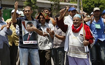Supporters of Egypt's ousted President Mohammed Morsi chant slogans at a sit-in in Nasser City, suburb of Cairo, Egypt, Sunday, July 7. The Arabic on the poster of Morsi reads, 'No alternative to legitimacy.' (photo credit: AP/Paul Schemm)