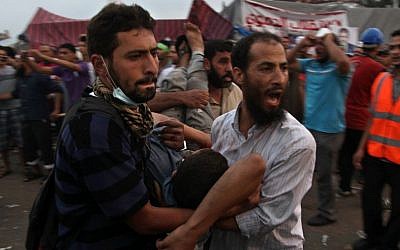 Supporters of Egypt's ousted President Mohammed Morsi carry an injured man to a field hospital following clashes with security forces at Nasr City, where pro-Morsi protesters have held a weekslong sit-in, in Cairo, Egypt, Saturday, July 27 (photo credit: AP/Khalil Hamra)
