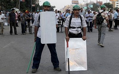 Supporters of Egypt's Islamist President Mohammed Morsi hold sticks and wear protective gear in Nasser City, in Cairo, Egypt, on Monday, July 1, 2013. (photo credit: AP Photo/Amr Nabil)