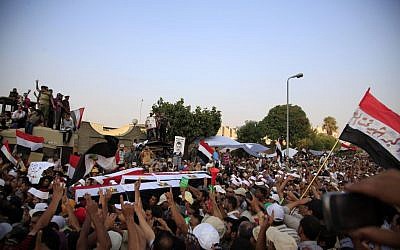 Supporters of Egypt's ousted President Mohammed Morsi carry coffins, covered with the national flag, of four men killed after Egyptian troops opened fire on mostly Islamist protesters marching on a Republican Guard headquarters Friday, in Cairo, Saturday, July 6, 2013. (photo credit: AP Photo/Khalil Hamra)
