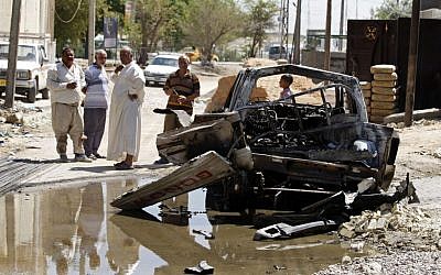 Civilians inspect the aftermath of a car bomb attack in Baghdad, Iraq, Wednesday, July 24, 2013 (photo credit: AP/Karim Kadim)