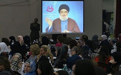 People watch Hezbollah leader Sheik Hassan Nasrallah deliver a televised speech in a southern suburb of Beirut, Lebanon on Wednesday (photo credit: AP/Hussein Malla)