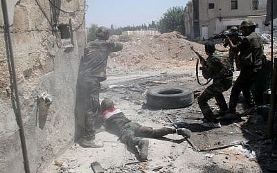 Syrian army personnel shoot toward rebel fighters during a tour for journalists organized by the Syrian Information Ministry in Damascus, Sunday, July 14, 2013. (photo credit: AP/Bassem Tellawi)