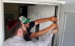 Illustrative: Rabbi Chaim Bruk, left, and Jake Matilsky affix a mezuzah to Matilsky's doorway in Helena, Montana, on June 30, 2013. (photo credit: AP/Matt Volz)