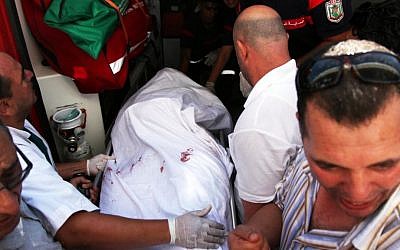 In this July 25 photo, the body of Tunisian opposition politician Mohammed Brahmi is carried into an ambulance at Mahmoud Materi hospital, north of Tunis, Tunisia. Mohammed Brahmi was shot 14 times in front of his home within sight of his family on Thursday, plunging the country into a political crisis and unleashing demonstrations around the country blaming the government for the assassination. (photo credit: AP Photo)