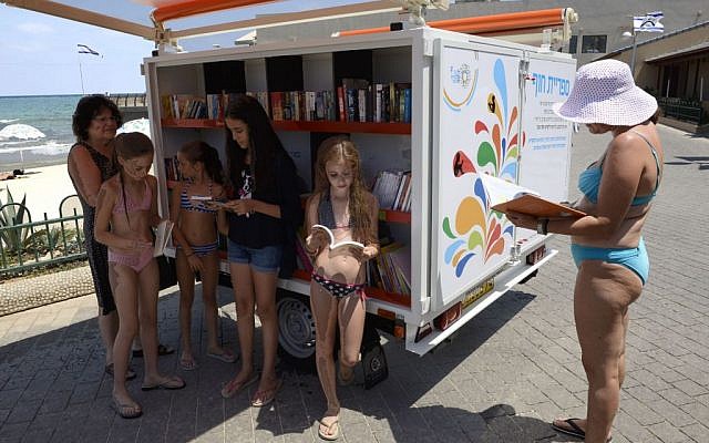 Beachgoers take a look at the library's collection. (Photo credit: Malovani Israel)