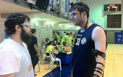 Joseph Gorowitz (left) helps a Russian player don tefillin after a basketball match (photo credit: Raphael Gellar/Times of Israel)