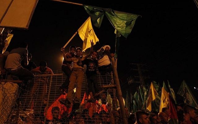 Palestinians celebrate and wave green Hamas and yellow Fatah flags as they wait for the released prisoners at a checkpoint at the entrance of Beit Hanoun between the northern Gaza Strip and Israel on Tuesday, Aug. 13, 2013. (photo credit: AP photo/Hatem Moussa)