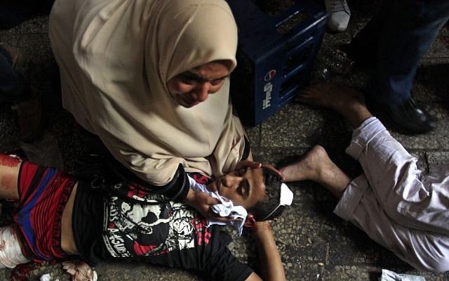 Injured Egyptians lay on the ground in Ramses Square, in Cairo, on Friday (photo credit: AP/Khalil Hamra)