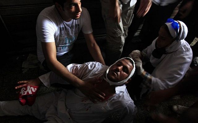 A wounded Egyptian man receives treatment on the ground during clashes between security forces and supporters of Egypt's ousted president Mohammed Morsi in Ramses Square, near the Al-Fath mosque, in downtown Cairo, Egypt, on Friday. (photo credit: AP Photo/Khalil Hamra) A wounded Egyptian man receives treatment on the ground during clashes between security forces and supporters of Egypt's ousted president Mohammed Morsi in Ramses Square, near the Al-Fath mosque, in downtown Cairo, Egypt, on Friday. (photo credit: AP Photo/Khalil Hamra)