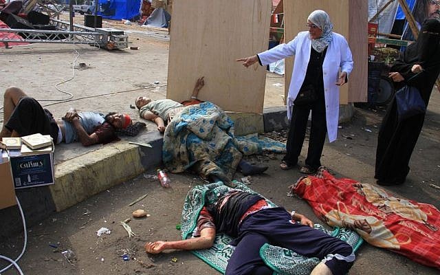 Injured supporters of ousted Islamist President Mohammed Morsi lie on the ground after Egyptian security forces clear a sit-in camp set up by supporters of Morsi in Nasr City district, Cairo, Egypt, Wednesday, Aug. 14, 2013. (Photo credit: AP/Ahmed Gomaa)