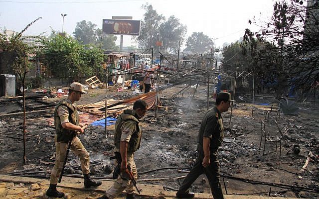 Egyptian soldiers walk among the smoldering remains of the largest protest camp of supporters of ousted president Mohammed Morsi, which was cleared by security forces, in the district of Nasser City in Cairo on Thursday. (photo credit: AP/Ahmed Gomaa)