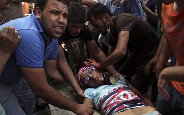 Egyptians evacuate a wounded young man during clashes between security forces and supporters of Egypt's ousted president Mohammed Morsi in downtown Cairo, on Friday (photo credit: APKhalil Hamra) Egyptians evacuate a wounded young man during clashes between security forces and supporters of Egypt's ousted president Mohammed Morsi in downtown Cairo, on Friday (photo credit: APKhalil Hamra)