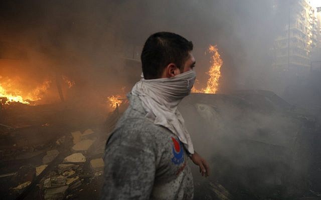 A Hezbollah civil defense worker walks past a burned car at the site of a bombing in a southern suburb of Beirut, Lebanon, Thursday, August 15, 2013 (photo credit: AP/Hussein Malla) A Hezbollah civil defense worker walks past a burned car at the site of a bombing in a southern suburb of Beirut, Lebanon, Thursday, August 15, 2013 (photo credit: AP/Hussein Malla)