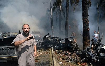 A Lebanese man takes pictures with his mobile phone at the site of an explosion outside a mosque in the northern city of Tripoli, Lebanon, on Friday (photo credit: AP)