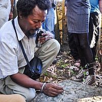 Danny Adeno Abebe, one of the organizers of the Samai trip for Ethiopian-Israeli teens, brushes grass from a Jewish cemetery outside Gondar, Ethiopia (photo credit: Michal Shmulovich/ToI)