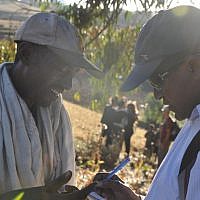 David Mihret, a prominent Ethiopian-Israeli community leader, asks a local Ethiopian farmer if he knows anything about the Jewish community that used to live in the area (photo credit: Michal Shmulovich/ToI)