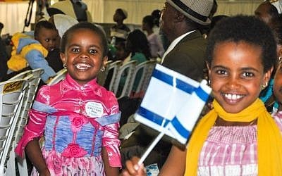 Two Falash Mura girls who became new Israelis in August 2013 wave their flags after reaching the airport (photo credit: Michal Shmulovich/ToI)