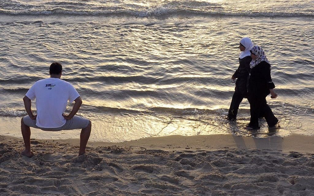 Palestininian women walk by an Israeli man on the beach in Tel Aviv. (photo credit: Serge Attal/Flash90) Palestininian women walk by an Israeli man on the beach in Tel Aviv. (photo credit: Serge Attal/Flash90)