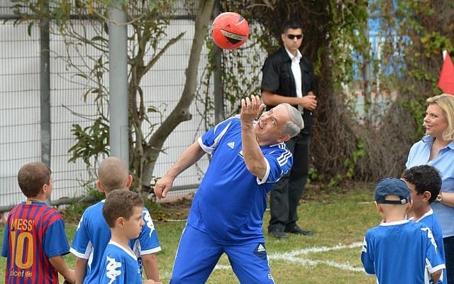 Prime Minister Benjamin Netanyahu plays with a soccer ball as he meets young cancer patients and the FC Barcelona soccer team, prior to FC Barcelona's open practice in Jaffa's Bloomfield Stadium, near Tel Aviv, Sunday, August 4, 2013 (photo credit: Avi Ohayon/GPO/Flash90)