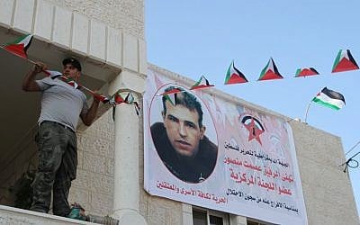 Family members of Esmat Mansour, on of 26 Palestinian prisoners being released early from Israeli prisons, hang up a welcome banner with his picture, outside his house in the West Bank village of Dier Jarer, near Ramallah, August 13, 2013. (photo credit: Issam Rimawi/Flash90) Family members of Esmat Mansour, on of 26 Palestinian prisoners being released early from Israeli prisons, hang up a welcome banner with his picture, outside his house in the West Bank village of Dier Jarer, near Ramallah, August 13, 2013. (photo credit: Issam Rimawi/Flash90)