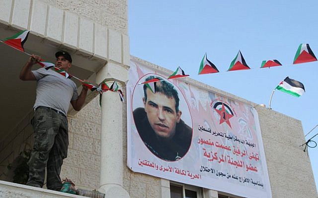 Family members of Esmat Mansour, on of 26 Palestinian prisoners being released early from Israeli prisons, hang up a welcome banner with his picture, outside his house in the West Bank village of Dier Jarer, near Ramallah, August 13, 2013. (photo credit: Issam Rimawi/Flash90)