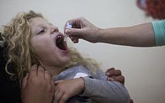 A child is inoculated with the oral polio vaccine at a children's health clinic in Jerusalem. (Yonatan Sindel/Flash90)