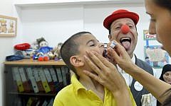 A medical clown makes faces as an Israeli boy receives polio vaccination, August 19, 2013. (Yossi Zeliger/Flash90)
