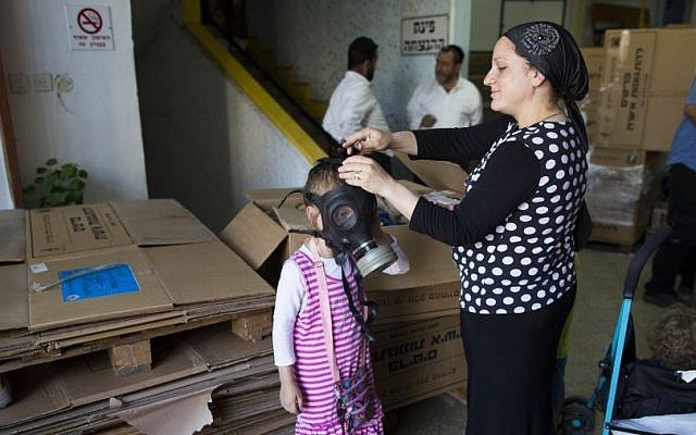 An Israeli woman shows her daughter how to put on a gas mask at a distribution center in Jerusalem, Tuesday, August 27, 2013 (photo credit: Yonatan Sindel/Flash90) An Israeli woman shows her daughter how to put on a gas mask at a distribution center in Jerusalem, Tuesday, August 27, 2013 (photo credit: Yonatan Sindel/Flash90)