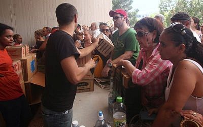 Israelis carry boxes with gas masks at a distribution center in Tel Aviv on August 28, 2013. (Photo credit: Roni Schutzer/Flash90)