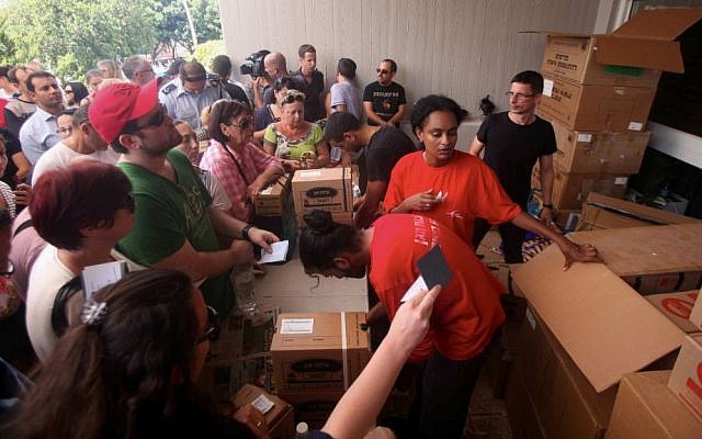 Israelis carry boxes with gas masks at a distribution center in Tel Aviv on August 28, 2013. (Photo credit: Roni Schutzer/Flash90) Israelis carry boxes with gas masks at a distribution center in Tel Aviv on August 28, 2013. (Photo credit: Roni Schutzer/Flash90)