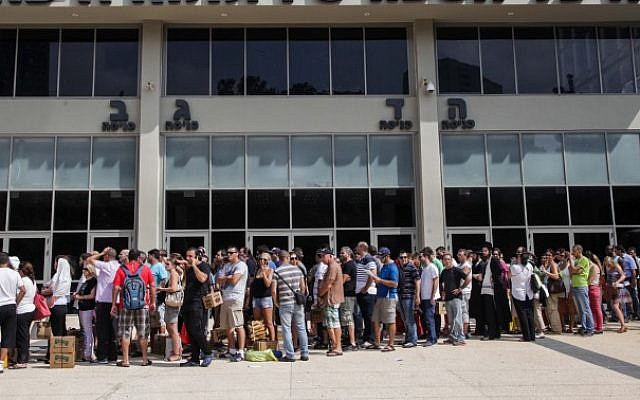 Israelis carry gas mask boxes outside a  distribution center in the northern Israeli city of Haifa, on August 29, 2013. (photo credit: Avishag Shaar Yashuv/Flash90)