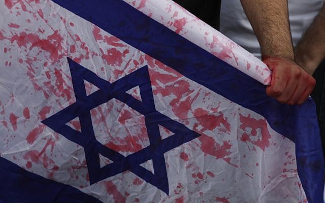 Relatives of Israelis killed in terror attacks hold up a flag with red paint on it to protest against the release of their loved one's killers (photo credit: Flash90) Relatives of Israelis killed in terror attacks hold up a flag with red paint on it to protest against the release of their loved one's killers (photo credit: Flash90)