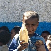 A young boy shows the bread and snacks he gets at the Jewish Agency-run synagogue in Gondar (photo credit: Michal Shmulovich/ToI)