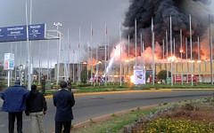 Onlookers watch as black smoke billows from the international arrivals hall of Jomo Kenyatta International Airport in Nairobi, Kenya, on Wednesday, August 7. (photo credit: AP/Segeni Ngethe)
