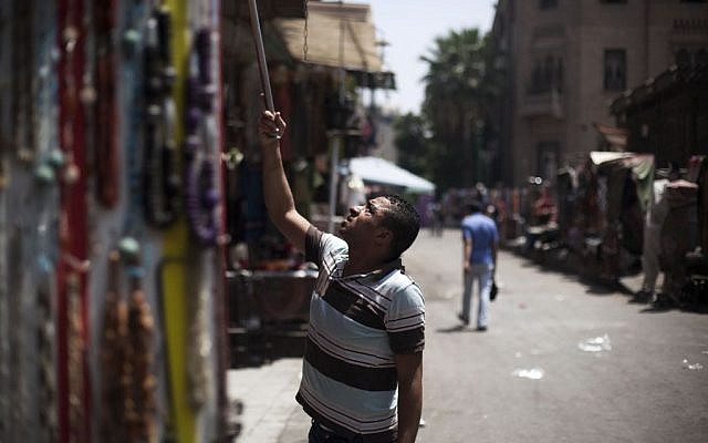 An Egyptian vendor hangs his stuff outside his souvenir store in the Khan El-Khalili market, normally a popular tourist destination, in Cairo, Egypt, Wednesday, August 21, 2013. (photo credit: AP Photo/Manu Brabo)